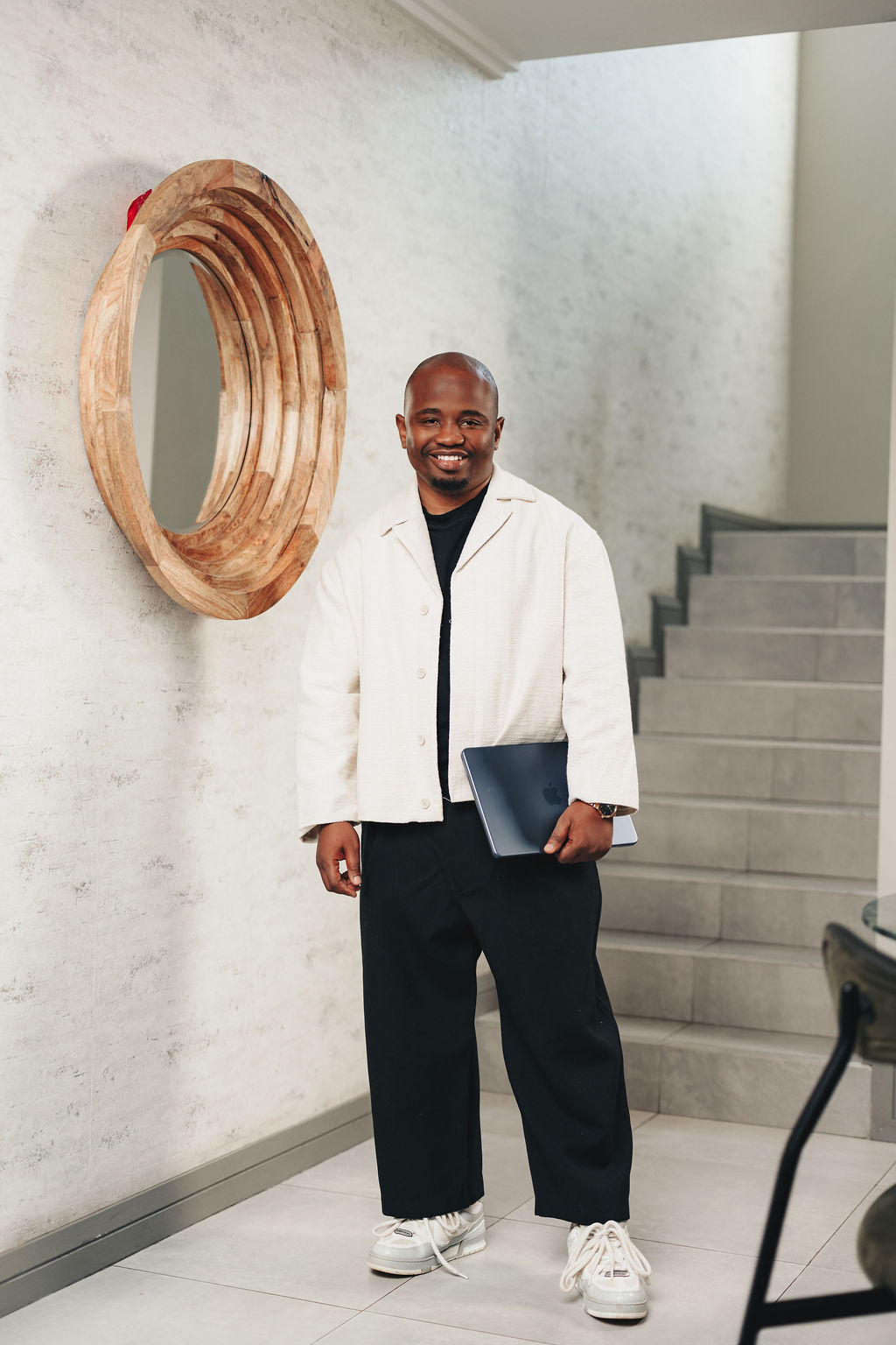 Dr Better standing with a laptop near a staircase